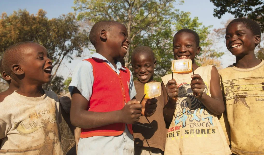 Boys in the off-grid community are smiling because they can use solar power